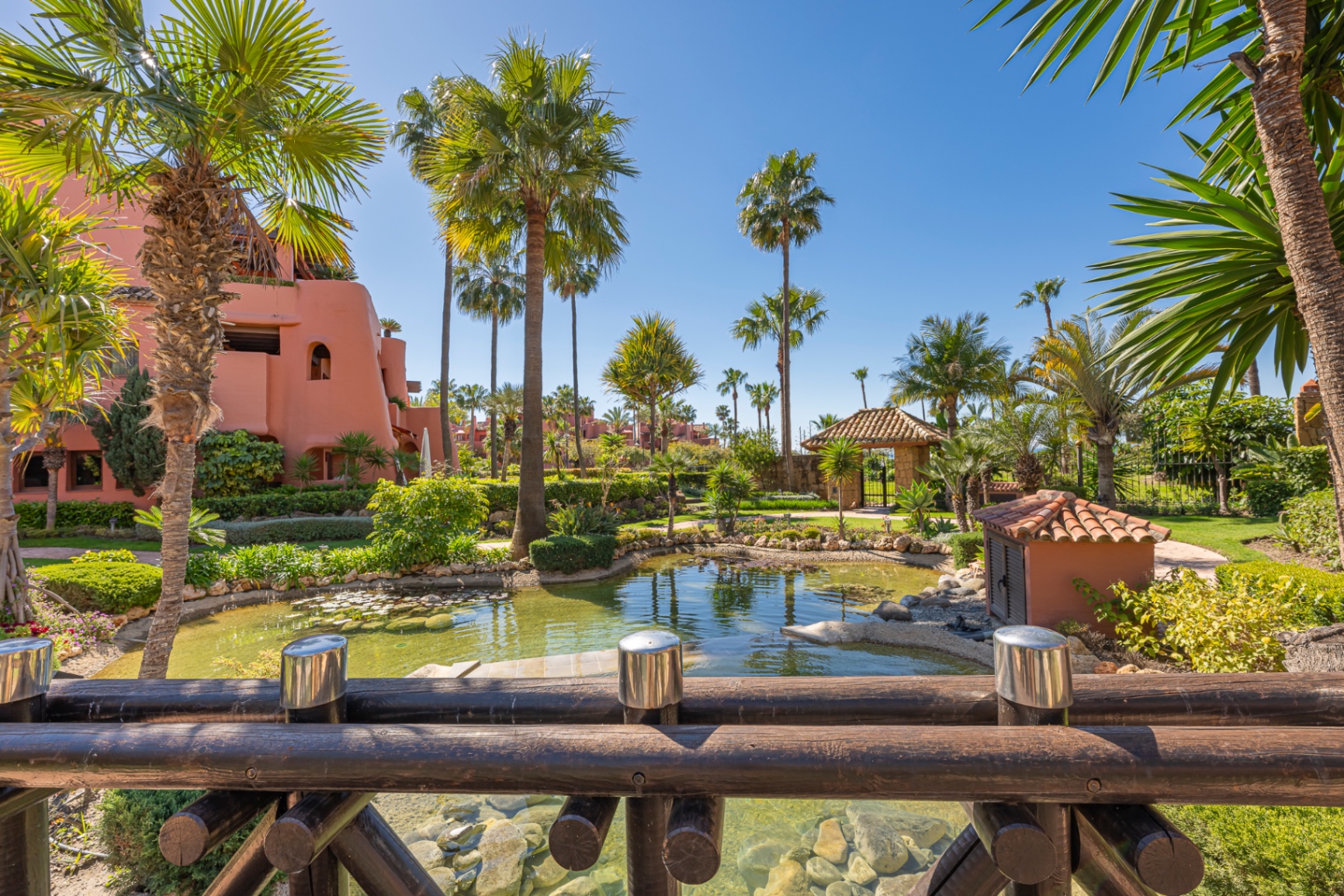 Palm-lined pond and traditional Andalusian architecture inside a beachfront residential community on the New Golden Mile.